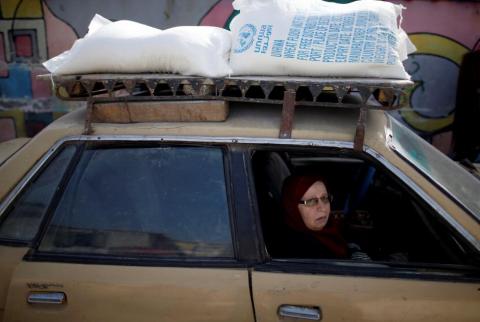 سيدة فلسطينية تستقل مركبة في مخيم الشاطئ تحمل مساعدات من "الأونروا-تصوير رويترز 80 % من سكان غزة يعتمدون على المساعدة الإنسانية