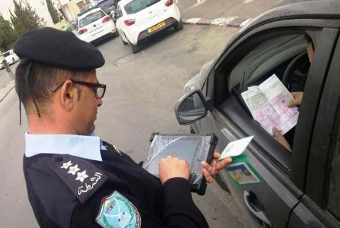 شرطي يدقق في أوراق مركبة-صورة توضيحية سلطة الترخيص: سحب رخصة قيادة كل من يتم ضبطه يقود مركبة غير قانونية