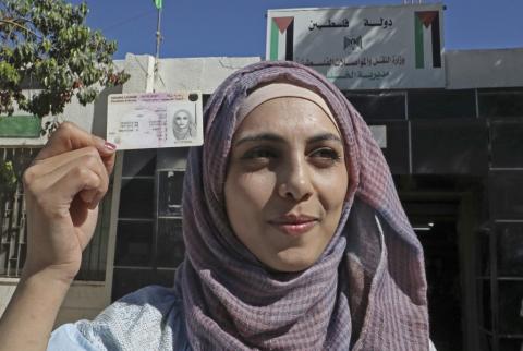 صورة توضيحية-شابة فلسطينة تعرض رخصة قيادتها بعد اجتيازها اختبار "قيادة شاحنة"-أرشيف أ ف ب فلسطين ورومانيا تعترفان بتبادل رخص القيادة الشخصية بين البلدين