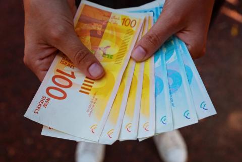 صورة توضيحية-رجل يحمل أوراق نقدية من فئتي 100و 200 شيكل-تصوير وكالات الناطق باسم الحكومة يتحدث عن موعد صرف الرواتب